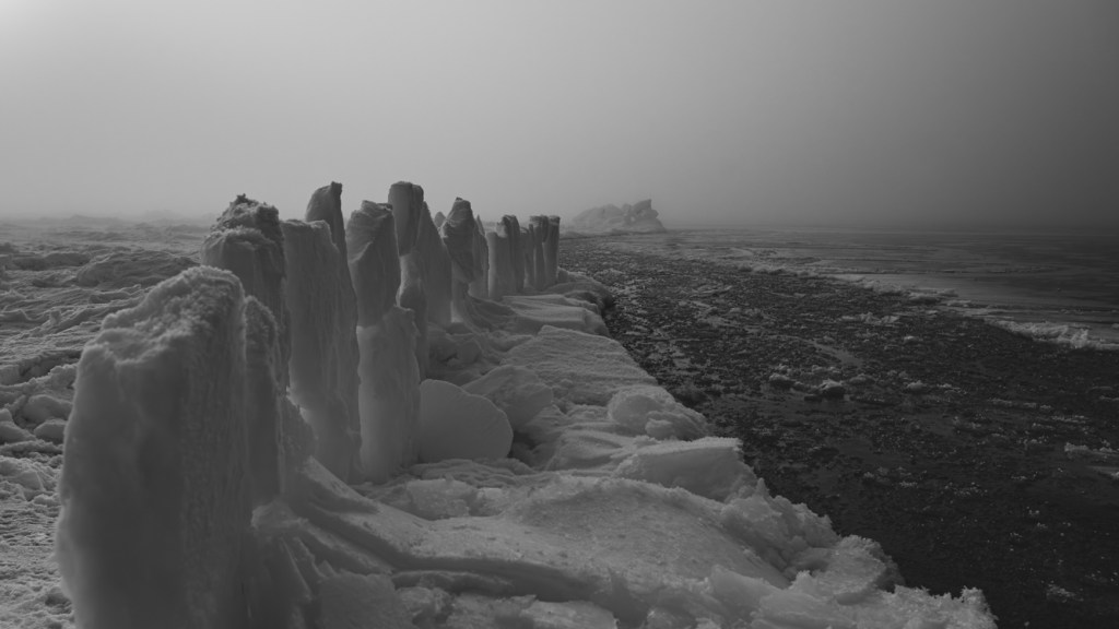Black and white photograph of a hunting blind made of large ice slabs positioned along the edge of Arctic sea ice by Inupiat whalers.
